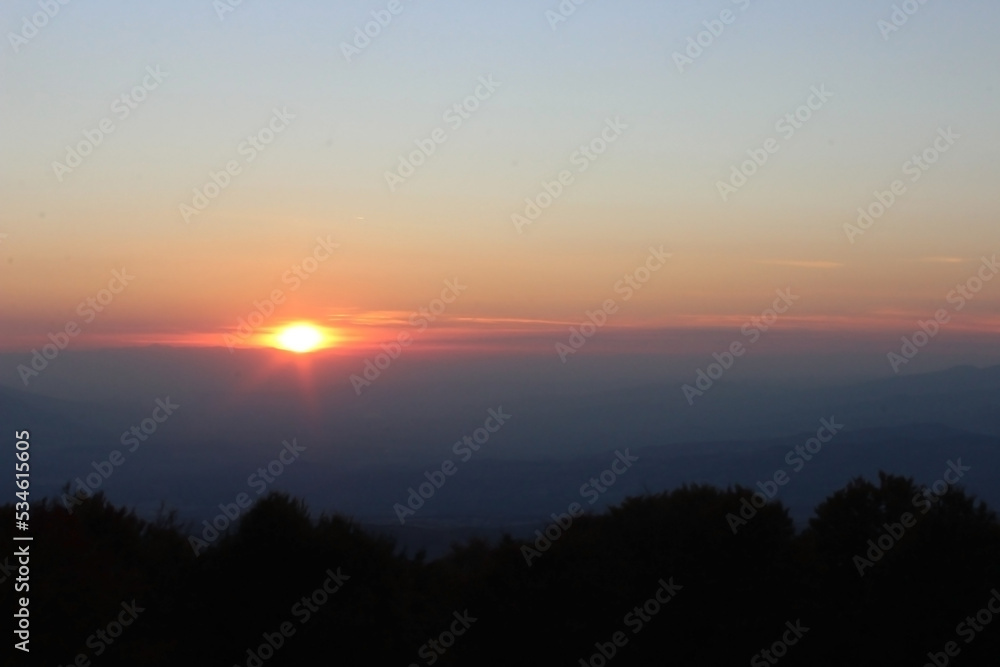 Sun before dawn over the mountains with cloudy sky 