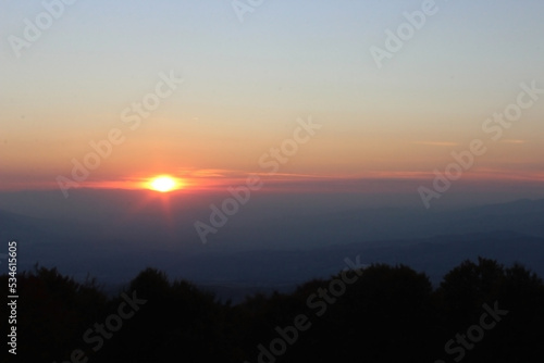 Sun before dawn over the mountains with cloudy sky 