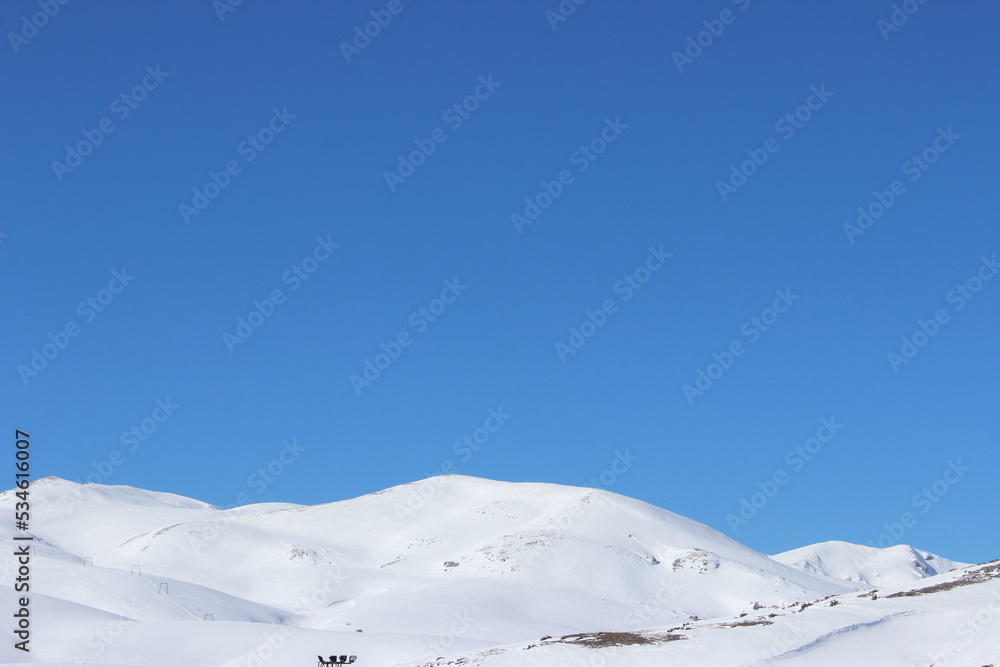 Beautiful landscape of mountains covered with white snow and clear blue sky in the background 