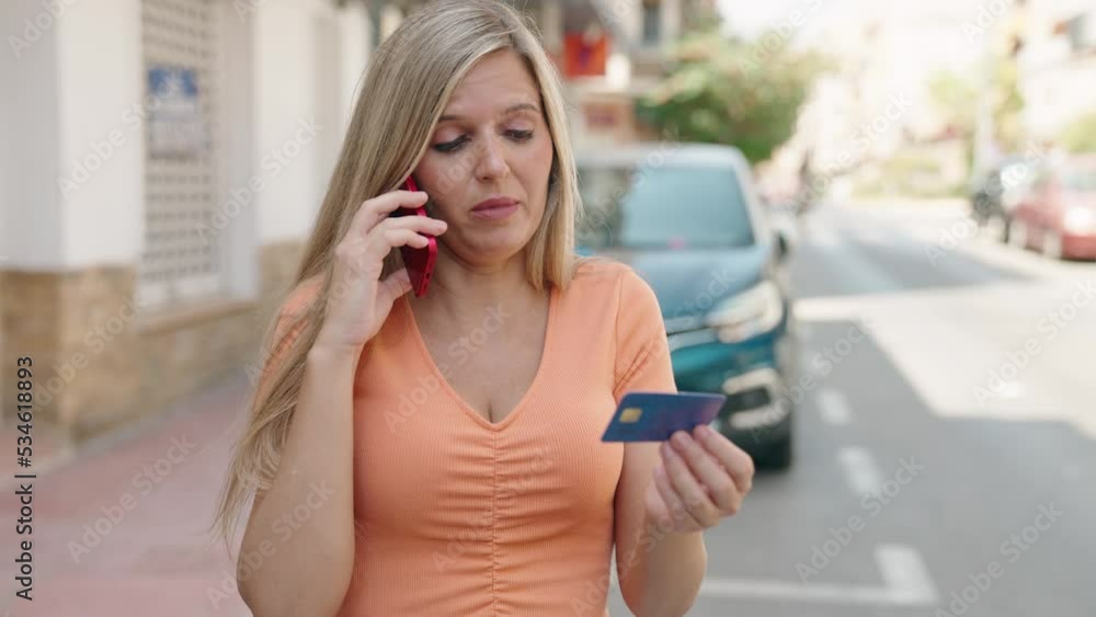 Young blonde woman talking on smartphone and credit card at street Young blonde woman talking on smartphone and credit card at street