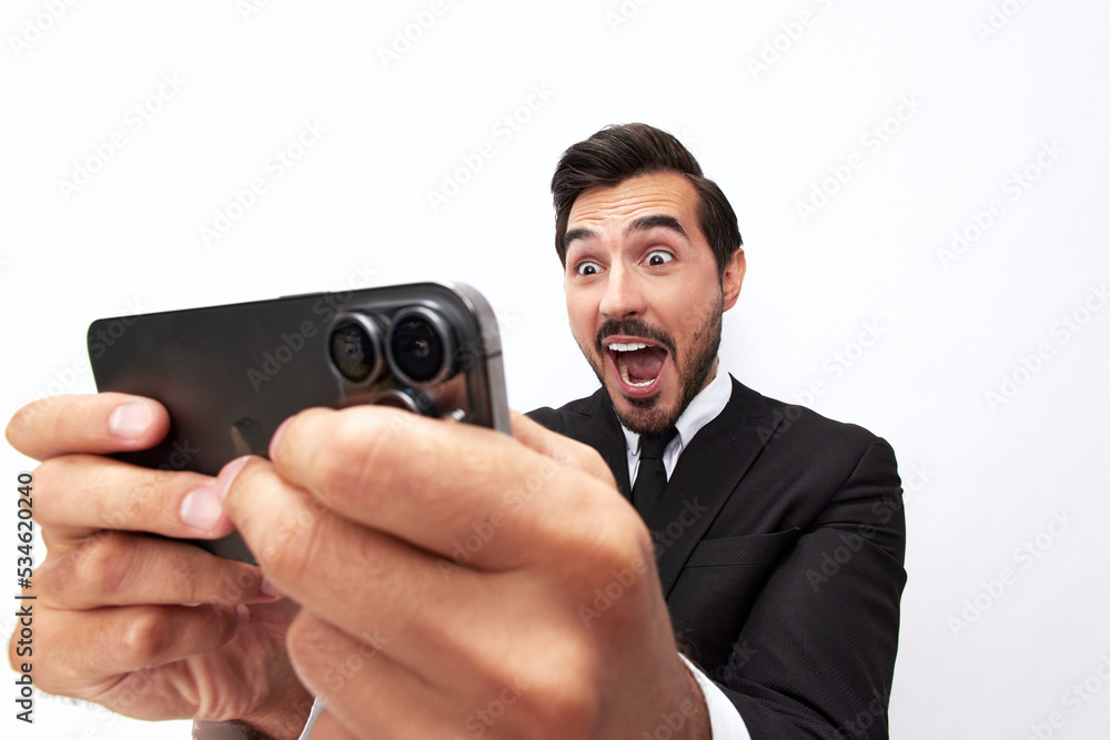 A male businessman gamer plays games on his phone and smiles happily with his teeth. Trading and winning at casinos online via phone. Close-up wide angle photo A male businessman gamer plays games on his phone and smiles happily with his teeth. Trading and winning at casinos online via phone. Close-up wide angle photo