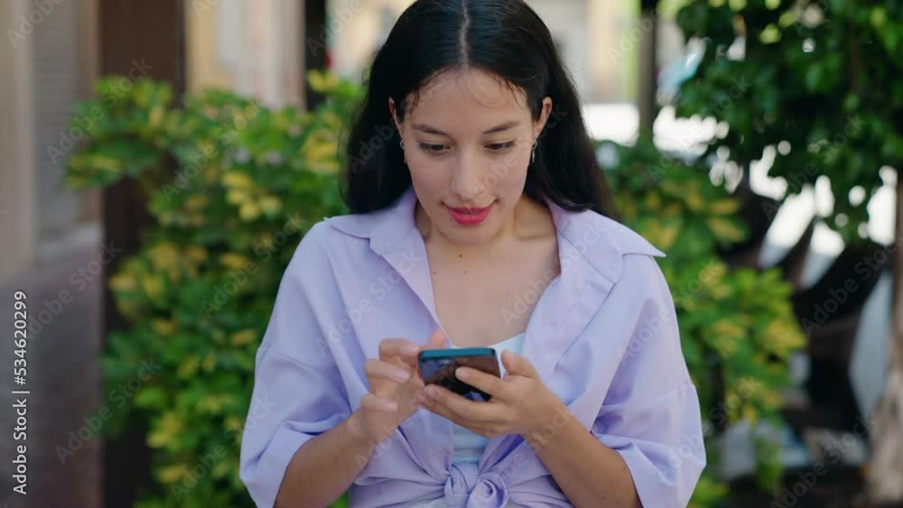 Young beautiful hispanic woman using smartphone with winner expression at street Young beautiful hispanic woman using smartphone with winner expression at street