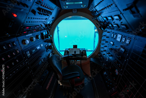 Cockpit of a submarine offering underwater cruises from Waikiki Beach in Honolulu, Hawaii - Round porthole with a steering wheel and dozens of switches used to make a submersible ship dive photo
