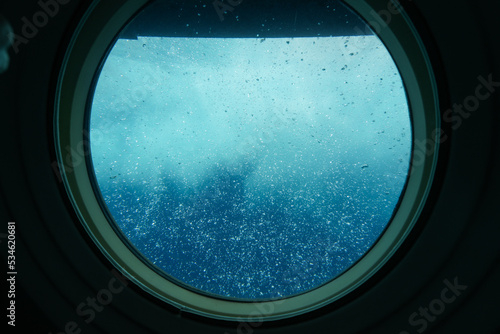 Bubbles visible through the porthole of a submarine surfacing in front of Waikiki Beach in Honolulu, Hawaii