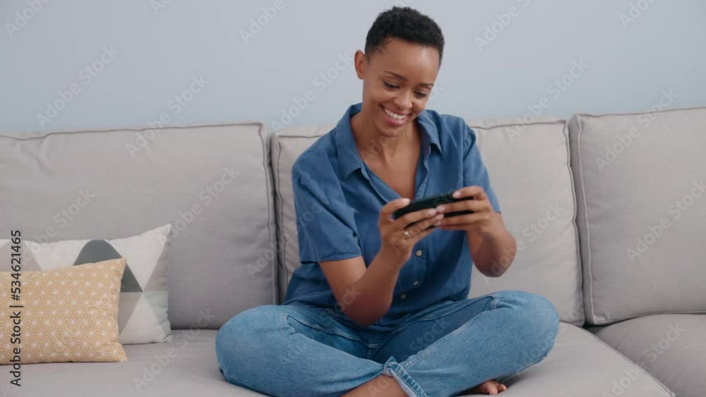 African american woman playing video game by smartphone at home African american woman playing video game by smartphone at home