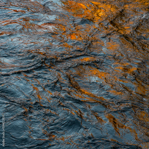 Abstract turquoise and gold image of reflections on actively moving water