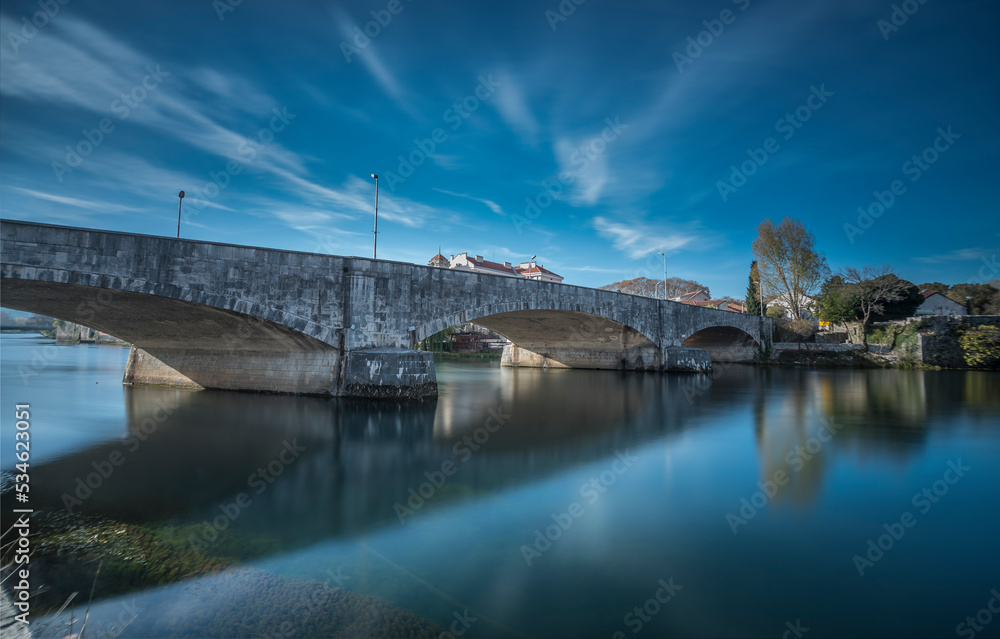 Trebinje view with beautiful reflection of old tonw on water and blue sky with white clouds and stone bridge