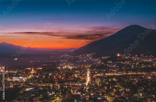 Trebinje city scape with evening lights and mountain with red sky after sunset