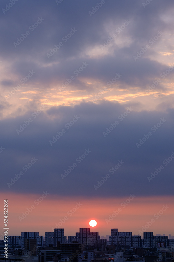 都市の夜明け。日の出とともに空と雲がオレンジ色に染まり、ビル群はシルエットとして写す 都市の夜明け。日の出とともに空と雲がオレンジ色に染まり、ビル群はシルエットとして写す