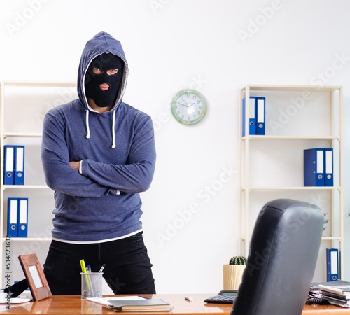 Male thief in balaclava in the office