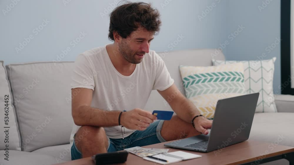 Young hispanic man using laptop and credit card at home Young hispanic man using laptop and credit card at home