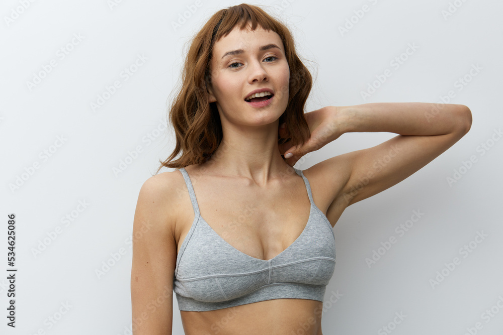 Fototapeta premium a beautiful, sexy, woman with tanned skin color and red hair stands on a white background holding her hand near her face