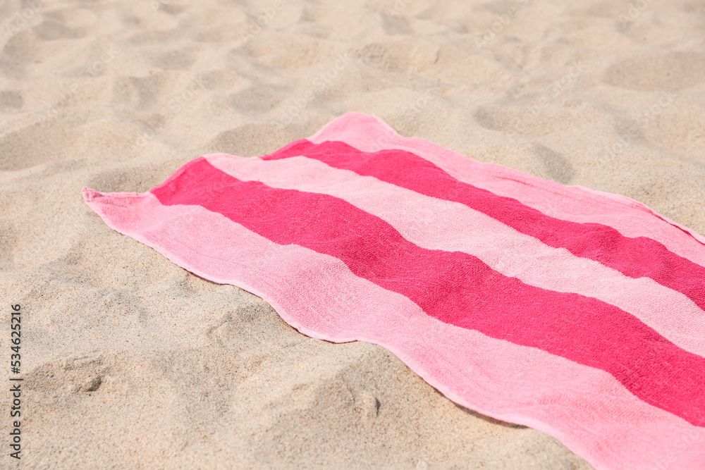 Soft pink striped towel on beach sand Soft pink striped towel on beach sand