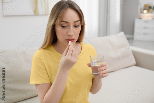 Young woman taking abortion pill at home