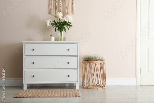 Room interior with white chest of drawers near beige wall. Space for text photo