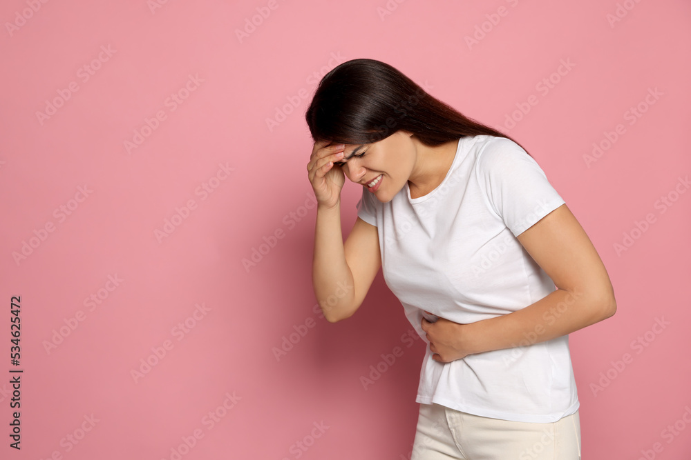 Young woman suffering from menstrual pain on pink background, space for text Young woman suffering from menstrual pain on pink background, space for text