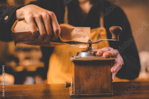 barista holding hand grinde...