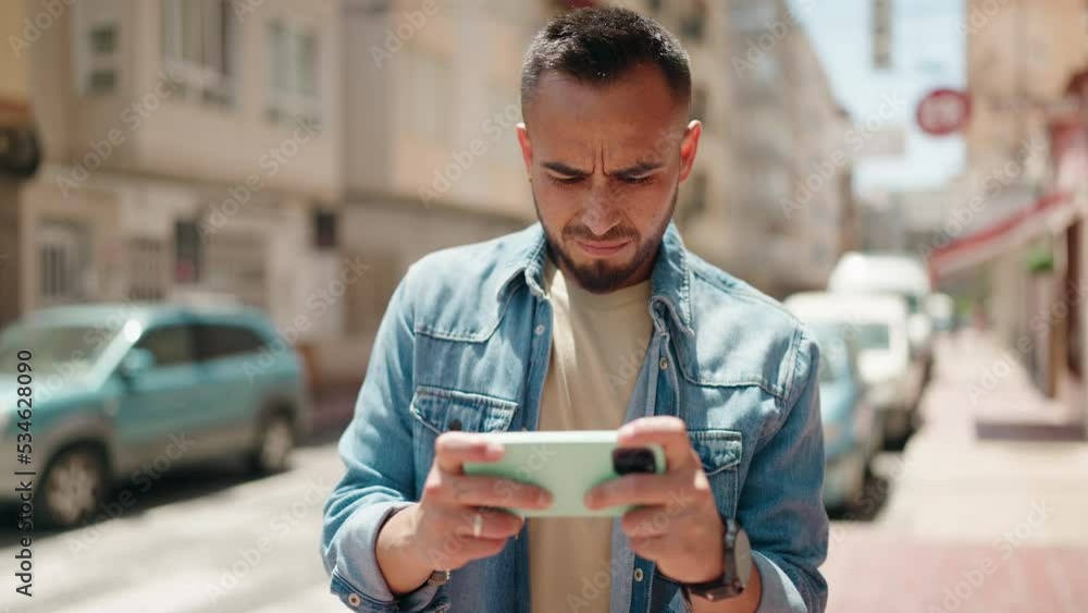 Young hispanic man smiling confident playing video game at street Young hispanic man smiling confident playing video game at street