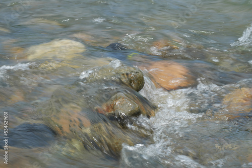 The water of a mountain river flowing over rocks, blurred in motion. Abstraction