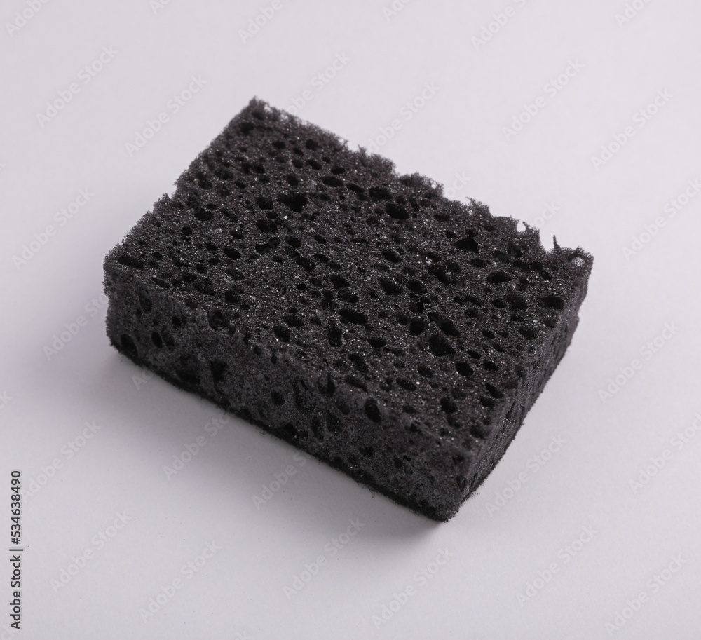 Black sponge for washing dishes on gray background Black sponge for washing dishes on gray background