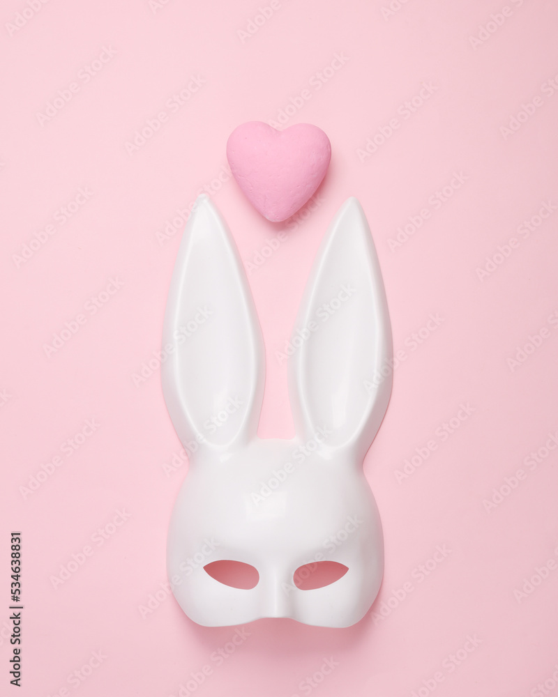 White rabbit mask with long ears from a sex shop and heart on pink pastel background. Love games White rabbit mask with long ears from a sex shop and heart on pink pastel background. Love games