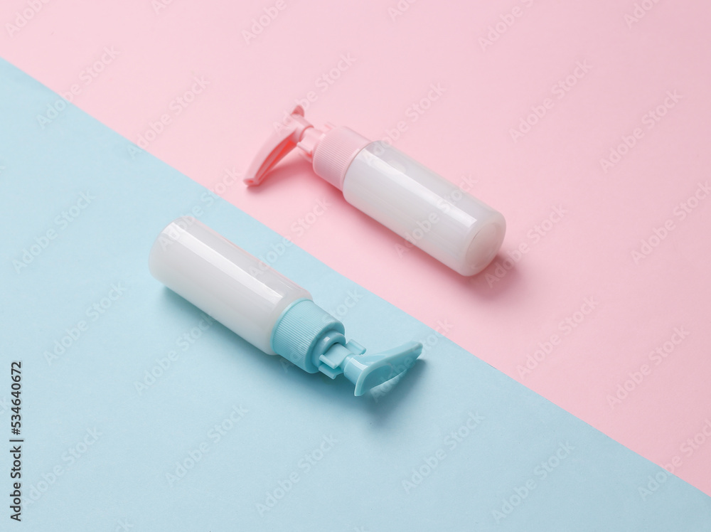 Bottles of cream or liquid soap with a dispenser on a blue-pink pastel background. Creative beauty still life Bottles of cream or liquid soap with a dispenser on a blue-pink pastel background. Creative beauty still life
