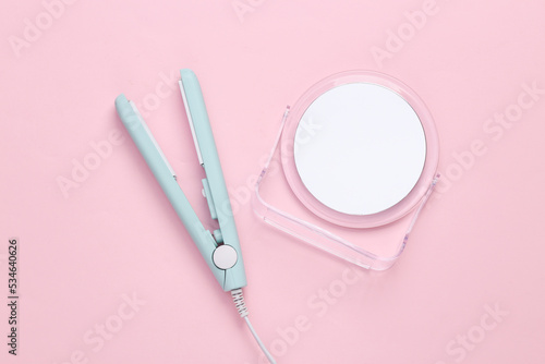 Hair straightener with mirror on a pink background