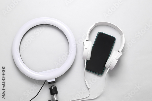 Led ring lamp with headphones and smartphone on a gray background. Gear for blogging and vlogging. Top view
