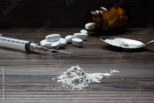 Foto Drugs set - powder and pills and syringe on wooden background