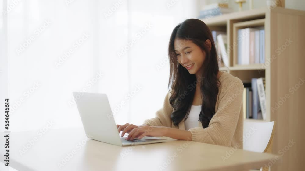 Young asian woman working at home. Female using computer laptop on desk at house Young asian woman working at home. Female using computer laptop on desk at house