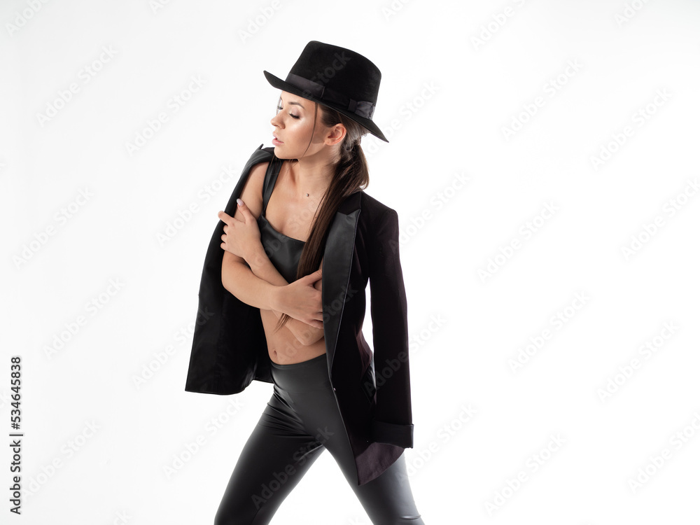 Stylish young woman in a black hat and jacket, posing on a white background in a photo studio Stylish young woman in a black hat and jacket, posing on a white background in a photo studio