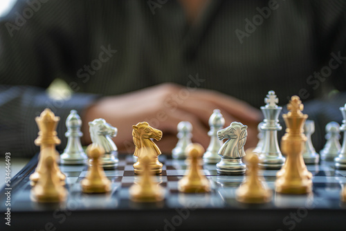 Businessman planning strategy with chess pieces on old wooden table A man is embracing the idea of playing chess at the conceptual table of sporting events and business.