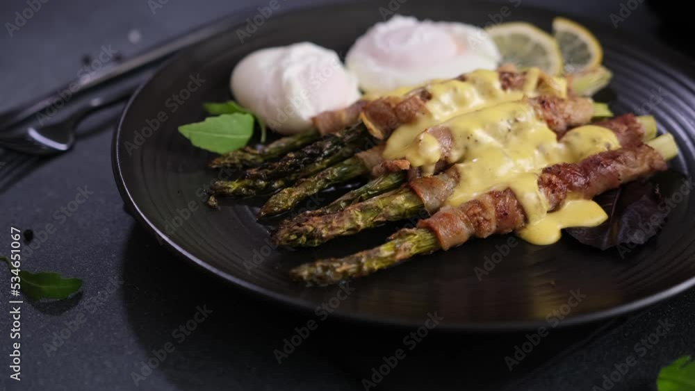 Baked asparagus wrapped with bacon, poached eggs on a plate and hollandaise sauce Baked asparagus wrapped with bacon, poached eggs on a plate and hollandaise sauce