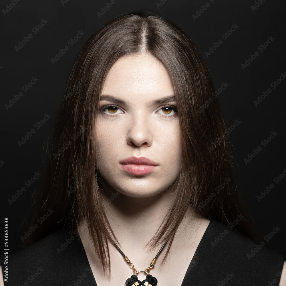 Beauty, make-up and fashion concept. Beautiful and young woman with long dark hair portrait. Model looking at camera in black studio background with copy space Beauty, make-up and fashion concept. Beautiful and young woman with long dark hair portrait. Model looking at camera in black studio background with copy space