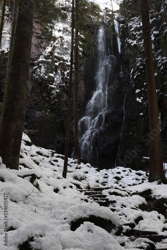 burgbach waterfall idyllically located in the forest between trees. Snowy landscape in winter from the German Black Forest photo