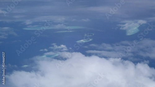 Clouds fly over the blue ocean and tropical islans reflecting on the surface of the water, aerial shot in the Indian Ocean photo