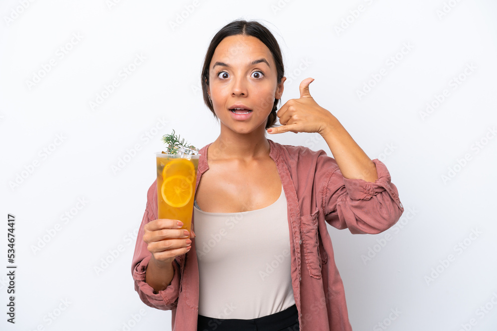 Young hispanic woman holding a cocktail isolated on white background making phone gesture. Call me back sign Young hispanic woman holding a cocktail isolated on white background making phone gesture. Call me back sign