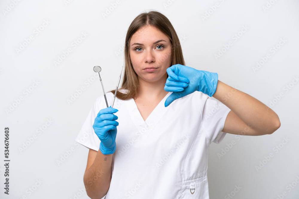 Dentist woman holding tools isolated on white background showing thumb down with negative expression Dentist woman holding tools isolated on white background showing thumb down with negative expression