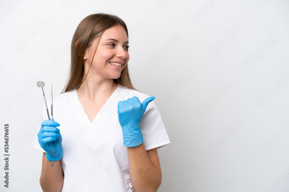 Dentist woman holding tools isolated on white background pointing to the side to present a product Dentist woman holding tools isolated on white background pointing to the side to present a product