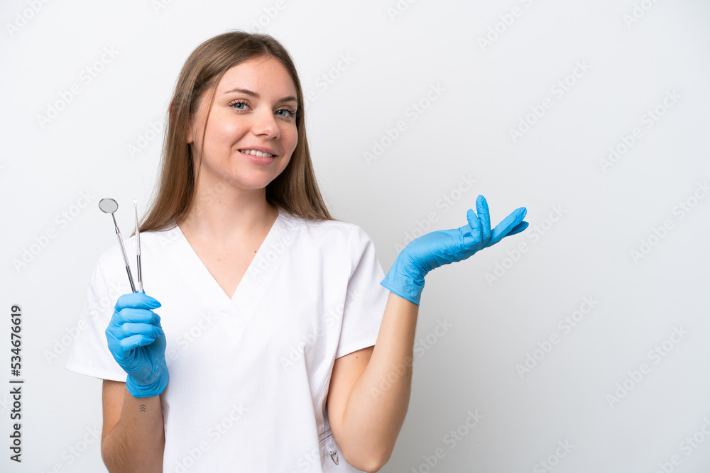 Dentist woman holding tools isolated on white background extending hands to the side for inviting to come Dentist woman holding tools isolated on white background extending hands to the side for inviting to come