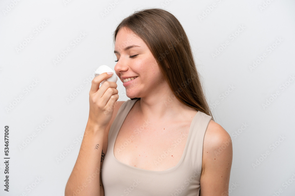 Young Lithuanian woman isolated on white background with moisturizer and smelling it Young Lithuanian woman isolated on white background with moisturizer and smelling it