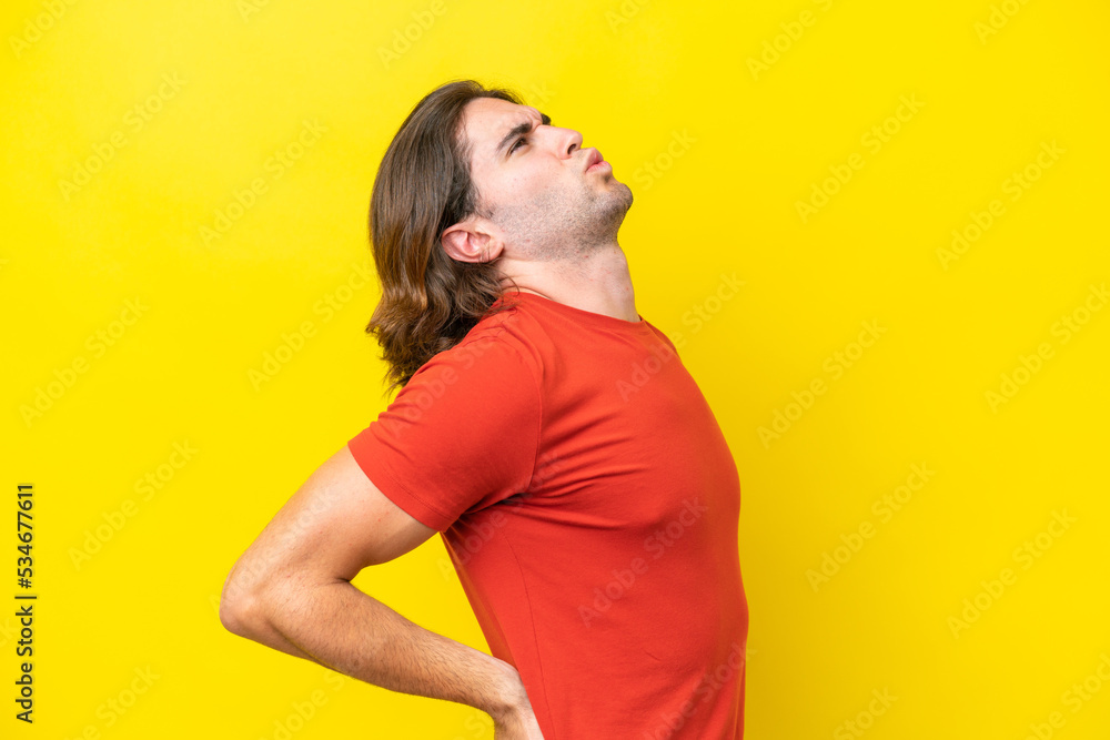 Caucasian handsome man isolated on yellow background suffering from backache for having made an effort Caucasian handsome man isolated on yellow background suffering from backache for having made an effort