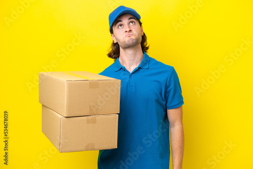 Delivery handsome man isolated on yellow background and looking up