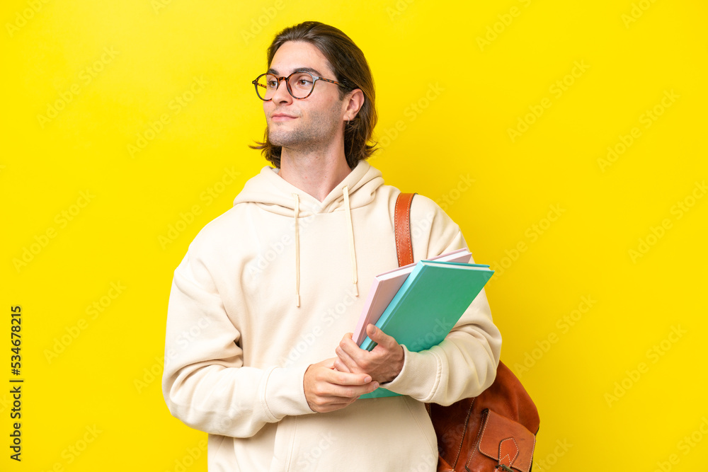 Young student handsome man isolated on yellow background looking to the side Young student handsome man isolated on yellow background looking to the side