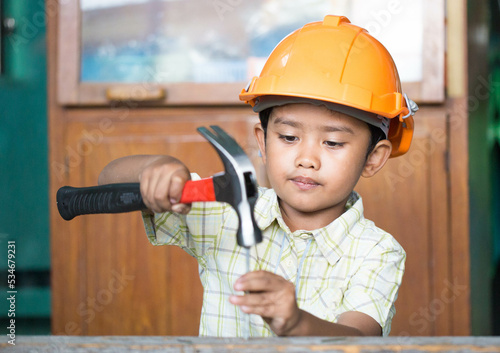 Asian boy dressed as a craftsman and holding tools 