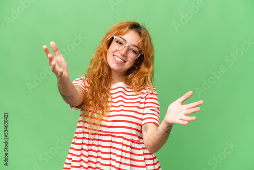 Foto Young caucasian woman isolated on green screen chroma key background presenting