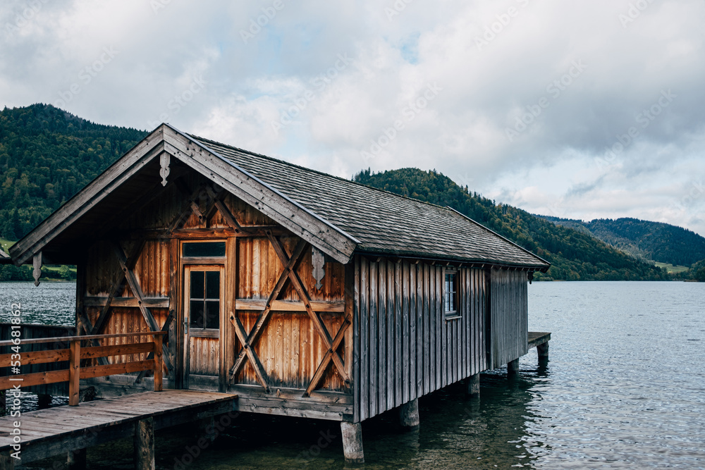 wooden boat house in lake in front of forest trees wooden boat house in lake in front of forest trees