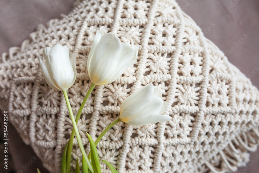 White pillows with macrame. Bed in a minimal bedroom scandinavian style. White tulip on macrame pillow White pillows with macrame. Bed in a minimal bedroom scandinavian style. White tulip on macrame pillow