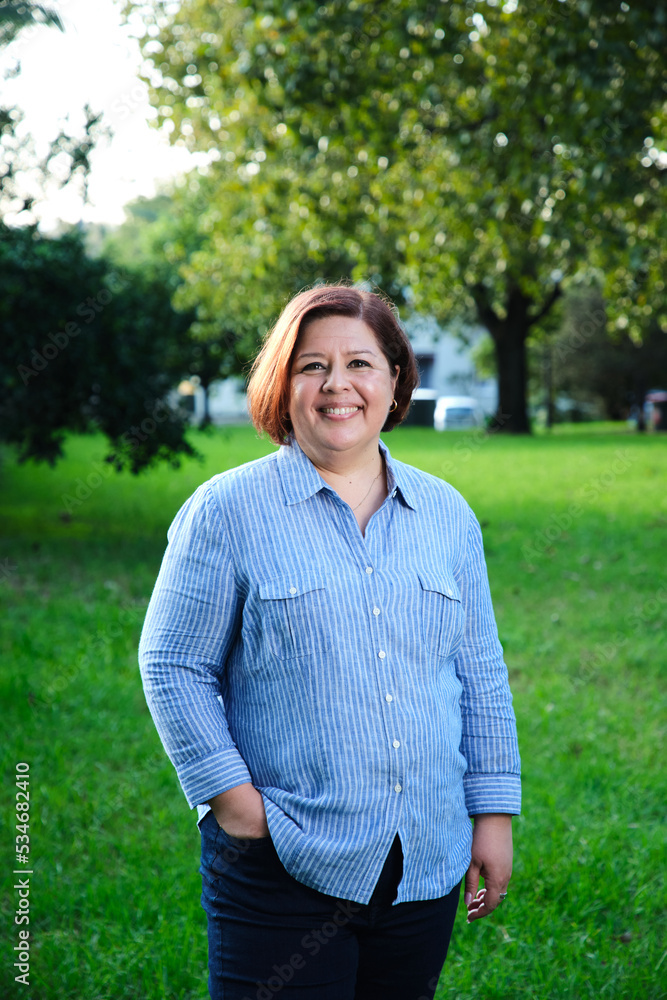 Smiling middle aged woman with short hair wearing blue and white striped shirt Smiling middle aged woman with short hair wearing blue and white striped shirt