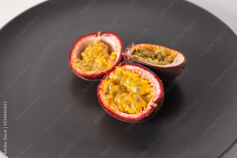 Passion fruit in section on a black plate Passion fruit in section on a black plate